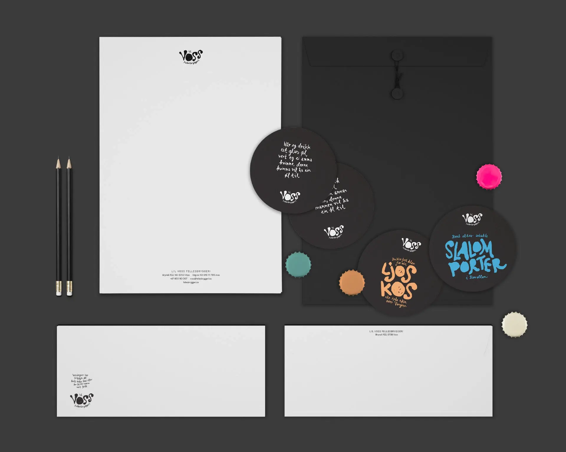 Stationery flatlay with Voss Fellesbryggeri letterhead, envelopes and hand-lettered coasters printed with product names, alongside pencils and bottle caps