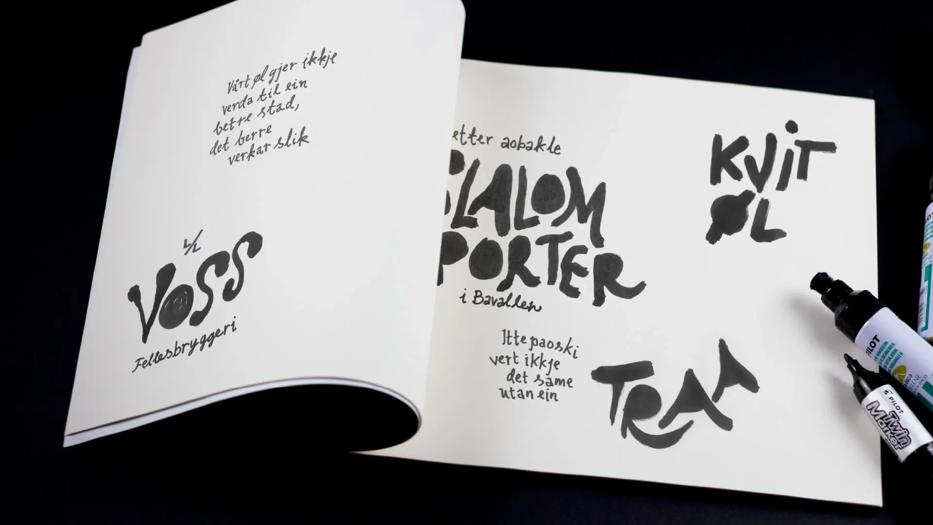 A sketchbook with hand-lettered Voss Fellesbryggeri logos and product names like "Slalom Porter", "Kvit øl" and "Traa", with marker pens resting beside it