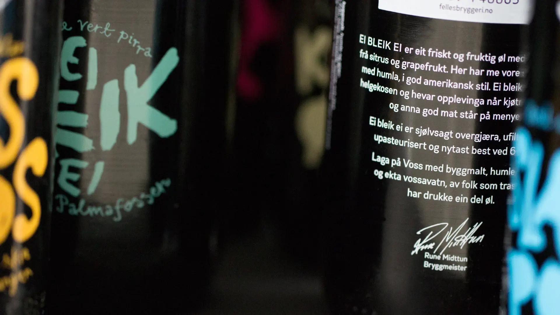 Nærbilde av Voss Fellesbryggeri-flasker med håndskrevet baksideetikett på ekte vossamål, signert av bryggmeister Rune Midttun